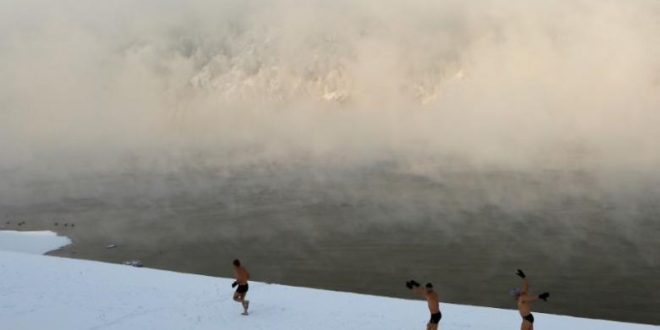 Enthusiasts of winter swimming warm up on the bank of the Yenisei River ahead of their weekly bathing session, with the air temperature at about minus 30 degrees Celsius (minus 22 degrees Fahrenheit), in the Siberian town of Divnogorsk, Russia November 18, 2016. REUTERS/Ilya Naymushin